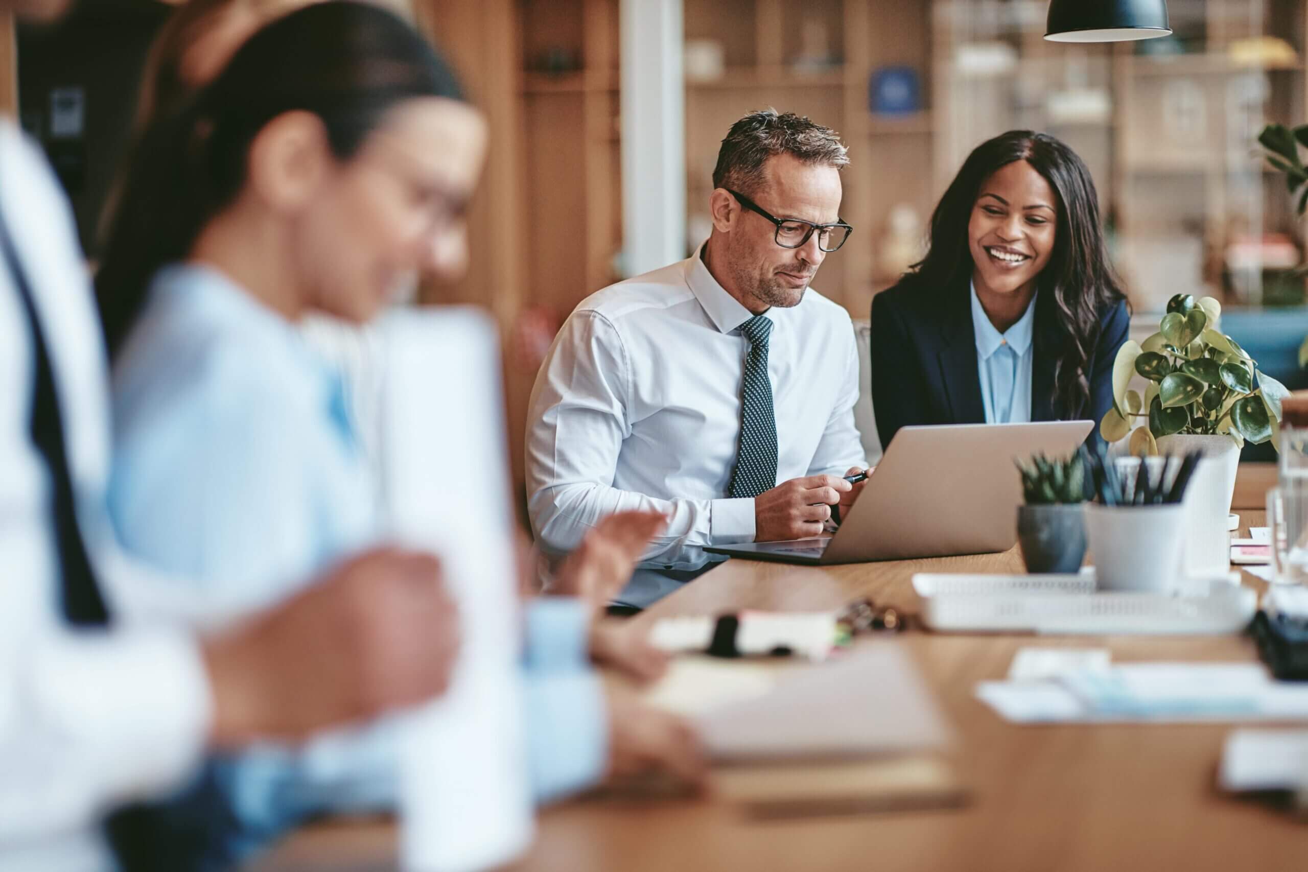 Reunião de equipe de trabalho com papéis e notebooks na mesa.