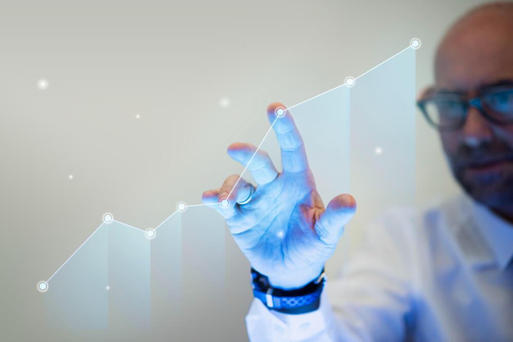 Homem toca gráfico digital em ascensão, simbolizando inovação no atendimento ao cliente com uso de tecnologia e análise de dados.