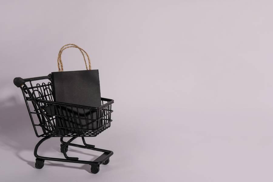 Carrinho de compras preto em miniatura com sacola preta, representando o atendimento na Black Friday.