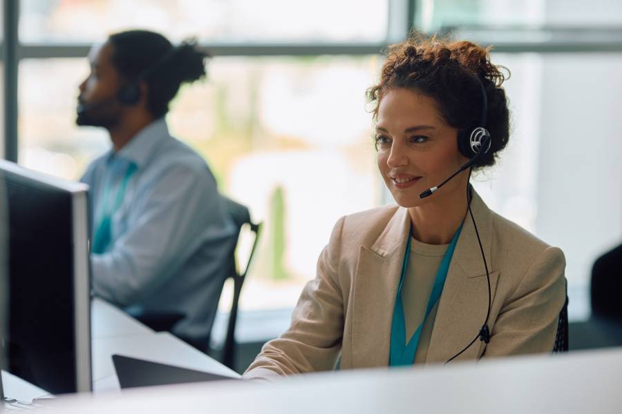 Atendente de suporte ao cliente usando headset em escrit&oacute;rio, realizando atendimento no e-commerce.