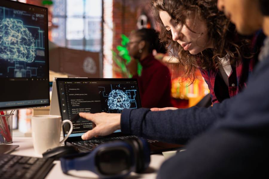 Dois colegas de trabalho em frente a dois monitores de computador enquanto usam IA para atendimento ao cliente