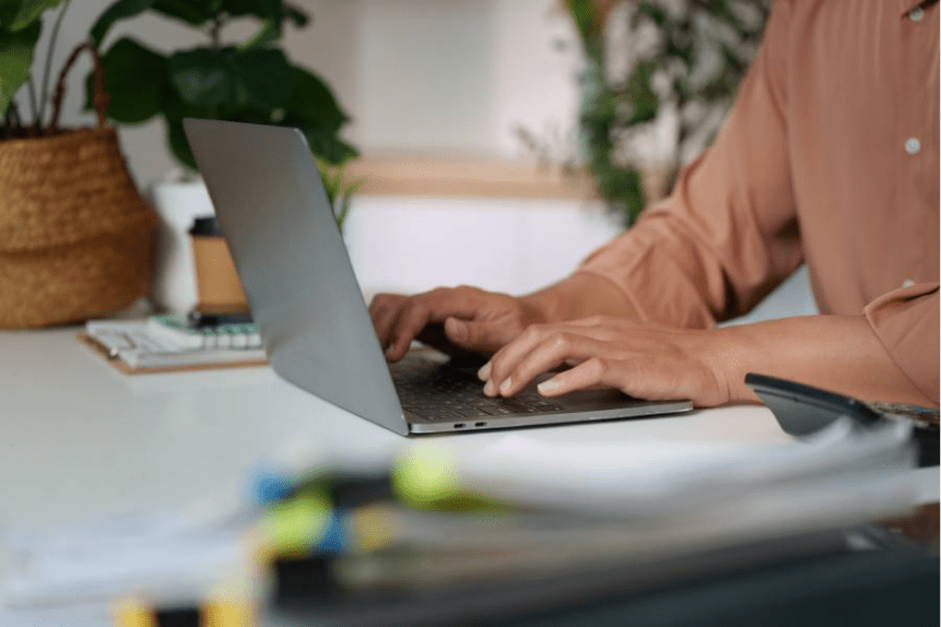 Pessoa digitando em laptop em ambiente de trabalho organizado, gerenciando estratégias de pós-venda online