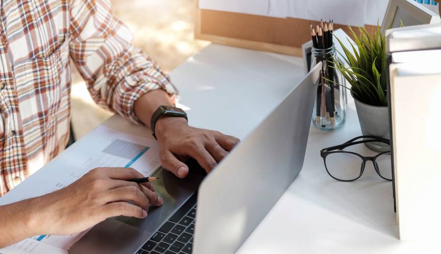 Profissional digitando no notebook em ambiente de trabalho para atendimento descentralizado.