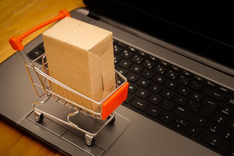 Carrinho miniatura com caixa sobre laptop, simbolizando vendas e pontos de penalidade da Shopee